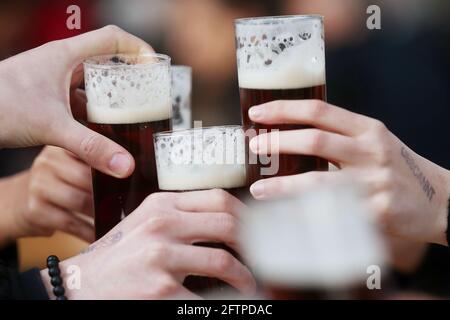 Duesseldorf, Germania. 21 Maggio 2021. Gli ospiti brindano con birra Alt a un tavolo nell'area esterna di un pub. Dopo un mese di pausa forzata, i ristoratori di Düsseldorf potranno accogliere nuovamente gli ospiti a partire da venerdì. Tuttavia, come in altri comuni della NRW, ciò vale solo per l'area esterna e a determinate condizioni. Credit: David Young/dpa/Alamy Live News Foto Stock