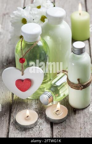 SPA Still Life, prodotti da bagno, candele accese, sfondo in legno, grigio verde, cuore rosso Foto Stock