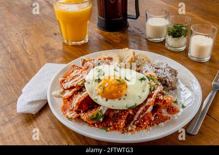 Colazione messicana tradizionale rosso peperoncino salsa di pomodoro succo d'arancia Tavola di legno Foto Stock