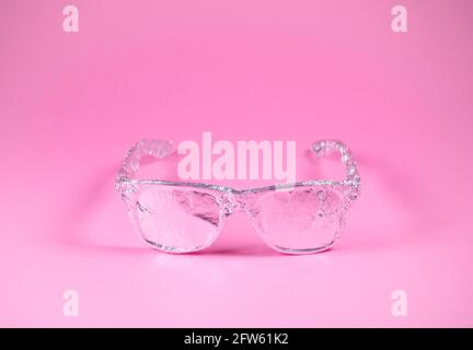 Occhiali da sole retrò avvolti in lamina di alluminio su sfondo rosa alla moda. Aspetto futuristico. Concetto estivo astratto minimo. Con spazio per la copia. Foto Stock