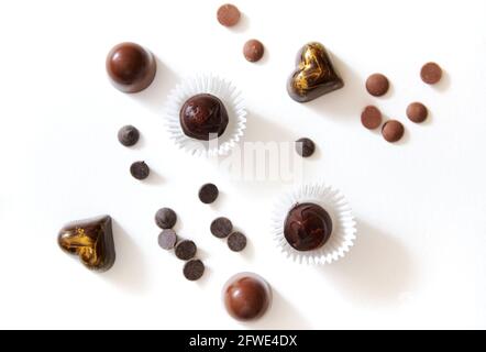 Composizione con varietà di tartufi di cioccolato di lusso fatti a mano, con splendidi ornamenti e tavolette di cioccolato sparse su superficie bianca con copy sp Foto Stock