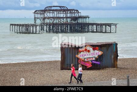 Brighton UK 22 maggio 2021 - i corridori passano dal vecchio contenitore di spedizione che è comparso sulla spiaggia di Brighton per promuovere il nuovo film di Netflix 'Army of the Dead' su una mattina soda inSeasonably fredda lungo la costa meridionale : Credit Simon Dack / Alamy Live News Foto Stock