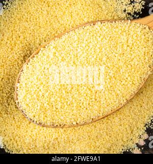 Vista dall'alto di grani di couscous nordafricani grezzi in legno primo piano del cucchiaio Foto Stock