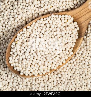 vista dall'alto del ptitim non cotti (couscous perla) in un cucchiaio di legno closeup Foto Stock
