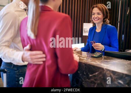 giovane adulto caucasico coppia di affari che effettua il check out alla reception in hotel Foto Stock