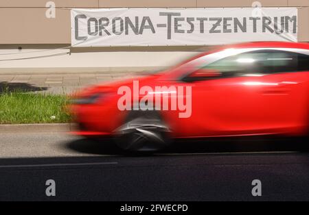 Dresda, Germania. 22 maggio 2021. Un'auto rossa passa accanto a un cartello con la scritta "Corona Test Centre" nel quartiere Johannstadt. Credit: Robert Michael/dpa-Zentralbild/dpa/Alamy Live News Foto Stock