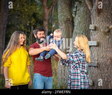 La famiglia passeggiate nel parco in estate, ha divertimento, giochi. Papà tiene il bambino tra le braccia Foto Stock