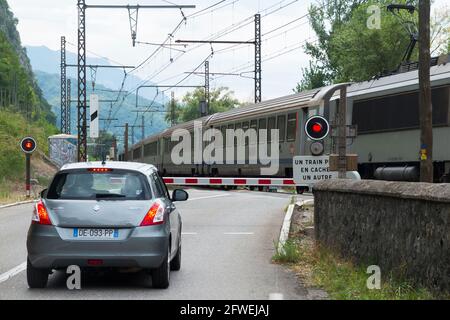 Il treno veloce passa e un segnale di traffico rosso mostra / lampeggiante / luci di avvertimento per un'auto ferma a una ferrovia francese ferrovia passaggio automatico a livello in Francia. (100) Foto Stock