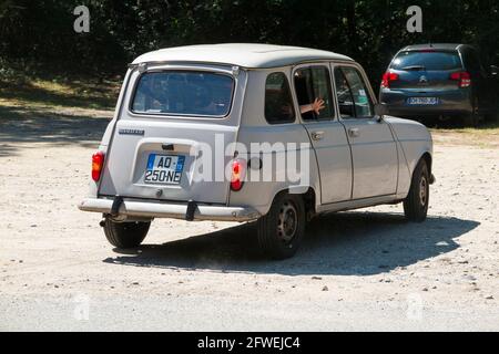 Conducente Renault 4 L guida su strada di campagna per parcheggi accidentati vicino a Seyssel in alta Savoia in Francia. Le persone all'interno della vettura 4L SONO modello rilasciato. Un braccio sta fornendo un segnale di indicazione della mano. (100) Foto Stock