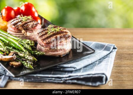 Bistecche alla griglia servite su un piatto con asparagi e pomodori freschi. Foto Stock