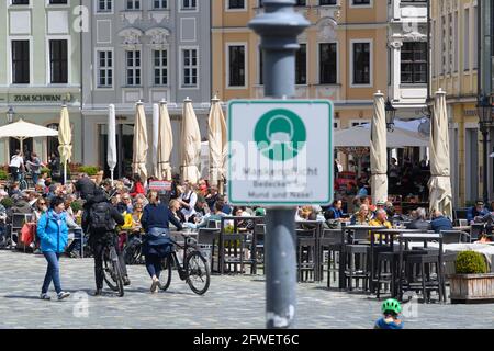 Dresda, Germania. 22 maggio 2021. La gente è seduta nella zona esterna di pranzo dei ristoranti e dei caffè a Neumarkt, in primo piano un segno per l'osservanza del requisito della maschera può essere visto su un palo della lampada. Credit: Robert Michael/dpa-Zentralbild/dpa/Alamy Live News Foto Stock