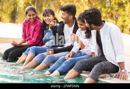 Concentratevi sul ragazzo medio, Gruppo di giovani millennial divertirsi e godersi un po' di tempo vicino alla piscina - concetto di amicizia, legame e. Foto Stock