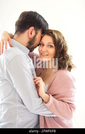 Vista laterale della coppia amorevole del soddisfare abbracciando delicatamente su bianco sfondo a casa Foto Stock