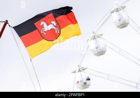 22 maggio 2021, bassa Sassonia, Bensersiel: Una bandiera della bassa Sassonia vola di fronte ad una ruota panoramica nel porto. Molti turisti sono attesi sulla costa e sulle isole sopra Whitsun. Foto: Hauke-Christian Dittrich/dpa Foto Stock