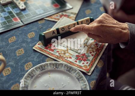 Mani della donna di generazione più anziana con artrite, gioco di lettere Foto Stock