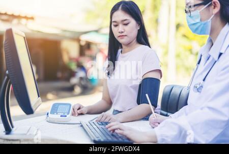 Dottore femminile misurazione della pressione sanguigna delle donne paziente servizio sociale nel villaggio locale Thailandia. Foto Stock