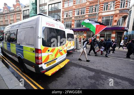 Un protestante con bandiera palestinese passa davanti ai poliziotti di Kensington, nel centro di Londra, dopo una marcia solidale con il popolo palestinese, a seguito di un accordo di cessate il fuoco tra Hamas e Israele. Data immagine: Sabato 22 maggio 2021. Foto Stock