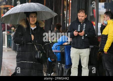 Una donna si rifuga dalla pioggia sotto un ombrello appena prima di un downpour torrenziale a Londra. Foto Stock