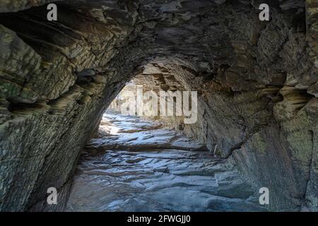 L'ingresso alla Grotta di Merlin, al Castello di Tintagel, a Tintagel, in Cornovaglia, Regno Unito Foto Stock