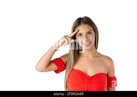 Bella donna latina che guarda avanti ondeggiando con la mano sulla fronte e con un atteggiamento felice su uno sfondo bianco puro. Foto Stock