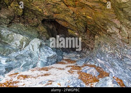 L'ingresso alla Grotta di Merlin, al Castello di Tintagel, a Tintagel, in Cornovaglia, Regno Unito Foto Stock