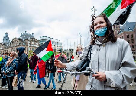 Amsterdam, Paesi Bassi. 22 maggio 2021. Una donna è vista ascoltare i discorsi mentre tiene una bandiera palestinese durante la dimostrazione.malgrado l'annuncio di un cessate il fuoco venerdì dopo una campagna di bombardamento israeliana di 11 giorni che ha ucciso più di 230 persone e gli attacchi missilistici palestinesi che hanno ucciso 12 in Israele, La comunità palestinese nei Paesi Bassi ha deciso di recarsi a Passi pure per il secondo fine settimana consecutivo con una manifestazione di solidarietà con il popolo palestinese organizzata nel centro di Amsterdam. Credit: SOPA Images Limited/Alamy Live News Foto Stock