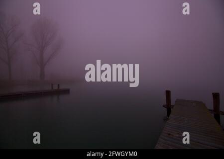 Ormeggia su un lago in una giornata di nebbia in inverno Foto Stock
