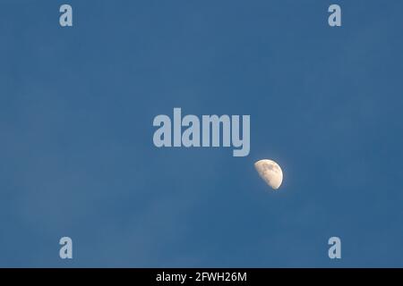 La luna è vista come una mezzaluna nel cielo serale con nuvole deboli nello spazio circostante negativo della copia. Foto Stock