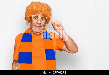 Alto uomo ispanico calcio hooligan tifoso gioco puntando il dito con successo idea. Uscito e felice. Numero uno. Foto Stock