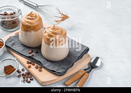 Caffè Dalgona in bicchieri trasparenti su sfondo grigio. Bevanda corroborante coreana. Spazio di copia. Foto Stock