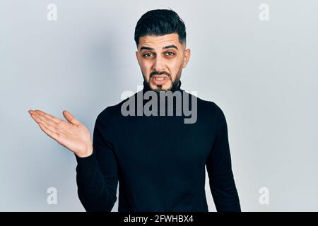 Bell'uomo con barba che si presenta con palma aperta indiziato e confuso espressione. Concetto di dubbio. Foto Stock