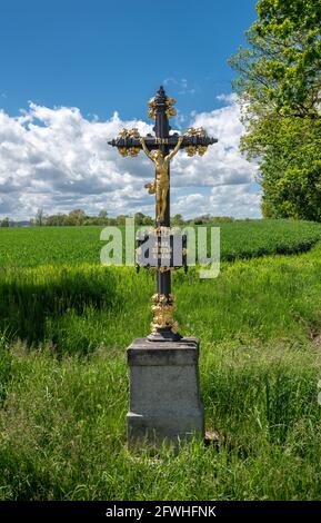 Una piccola croce di campagna al bordo di un campo con una statua di Cristo crocifisso e l'iscrizione 'Signore, stare con noi!' In ceco. Foto Stock