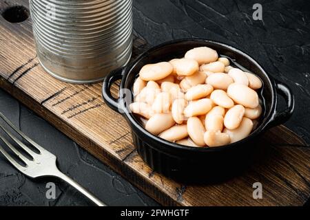 Set di fagioli bianchi in scatola, con lattina metallica, in ciotola, su fondo di pietra nera Foto Stock