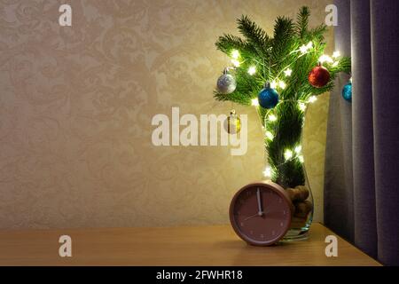 Bouquet di capodanno di rami di abete rosso, ghirlande e giocattoli di Natale sul comodino in camera da letto. Foto Stock