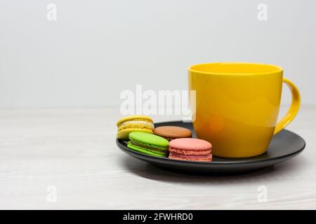 Macaroni multicolore su un piatto nero vicino a una tazza gialla Foto Stock