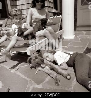 Il presidente John F. Kennedy (parzialmente nascosto), First Lady Jacqueline Kennedy, e i loro figli, Caroline Kennedy e John F. Kennedy, Jr., siedono con i loro cani, Wolf, White Tips, e Blackie, a casa Brambletyde su Squaw Island, Hyannis Port, Massachusetts. Foto Stock