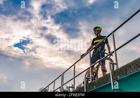 Ritratto del ciclista asiatico con bicicletta sportiva in posa sul ponte, vista dall'alto, immagine del tramonto, spazio vuoto per il testo. Foto Stock