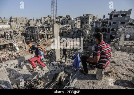 I palestinesi siedono tra le macerie delle loro case distrutte dopo il cessate il fuoco tra Israele e i militanti di Gaza nella città di Beit Hanoun, nella striscia di Gaza settentrionale. Dopo 11 giorni di combattimenti, il cessate il fuoco è entrato in vigore tra Israele e i militanti della striscia di Gaza sotto la supervisione di un'iniziativa egiziana per fermare il fuoco incondizionato. Almeno 232 palestinesi sono stati uccisi nell'attacco israeliano secondo il Ministero della Salute palestinese, mentre almeno 12 Israeliti sono stati uccisi in attacchi a razzo da Gaza. Foto Stock