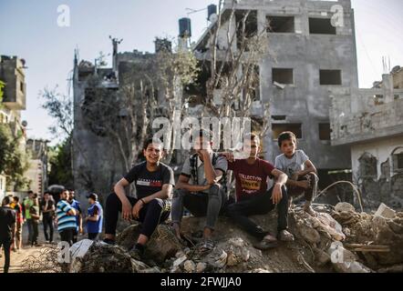 I palestinesi siedono tra le macerie delle loro case distrutte dopo il cessate il fuoco tra Israele e i militanti di Gaza nella città di Beit Hanoun, nella striscia di Gaza settentrionale. Dopo 11 giorni di combattimenti, il cessate il fuoco è entrato in vigore tra Israele e i militanti della striscia di Gaza sotto la supervisione di un'iniziativa egiziana per fermare il fuoco incondizionato. Almeno 232 palestinesi sono stati uccisi nell'attacco israeliano secondo il Ministero della Salute palestinese, mentre almeno 12 Israeliti sono stati uccisi in attacchi a razzo da Gaza. Foto Stock