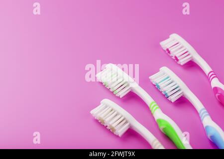 Quattro spazzolini da denti su sfondo rosa di fila. Spazio libero, isolamento, vista dall'alto Foto Stock