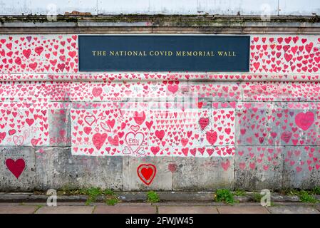 National Covid Memorial Wall in una giornata di lavoro a Lambeth, Londra, Regno Unito. Cuori rossi disegnati su un muro che rappresenta ogni morte di COVID 19. Erbacce Foto Stock