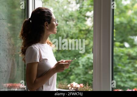 Giovane donna sognante con cellulare in mani che respirano aria fresca. Foto Stock