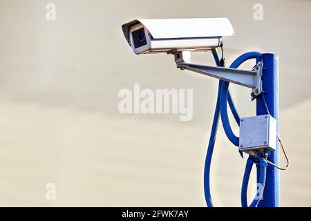 Si tratta di una telecamera di sicurezza appesa su un palo in una giornata estiva su uno sfondo grigio. Il sistema di tracciamento e protezione del perimetro del territorio. Spazio di copia. Foto Stock