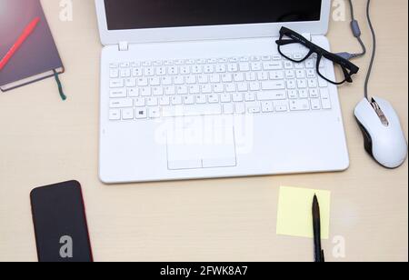 Elegante scrivania da ufficio con computer portatile, agenda e area di lavoro su sfondo bianco. Disposizione piatta Foto Stock