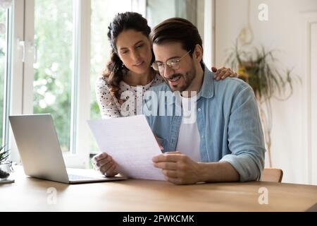 Felice affettuosa giovane coppia di famiglia che legge corrispondenza su carta. Foto Stock