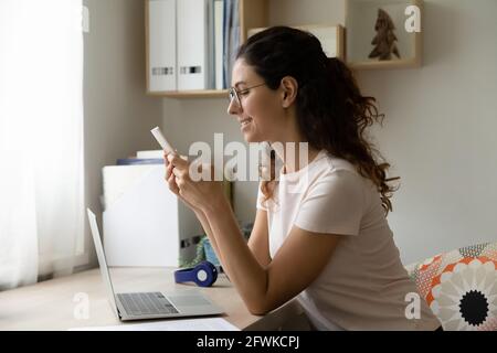 Giovane donna ispanica che utilizza l'applicazione per smartphone in ufficio. Foto Stock