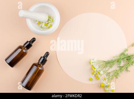 Concetto per la produzione di prodotti a partire da erbe naturali. Prodotto organico naturale. Un bouquet di margherite, due bottiglie di olio e un mortaio con margherite Foto Stock