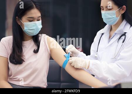 Flebotomista esperto che prepara il tourniquet una donna per il prelievo di sangue Foto Stock