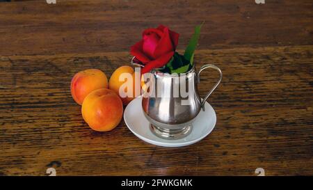 Frutta e rosa rossa su un vecchio tavolo Foto Stock