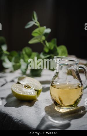 Caraffa di sidro di mele con mele verdi fresche su rustico sfondo Foto Stock